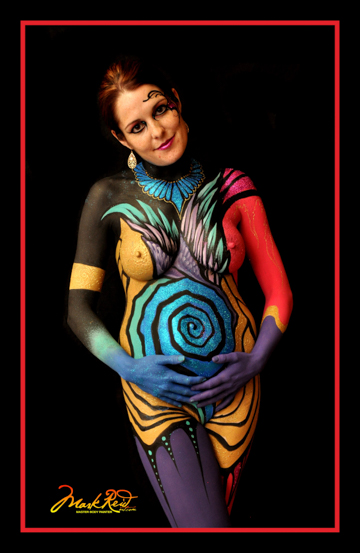 woman in full body paint with a spiral on her pregnant belly
