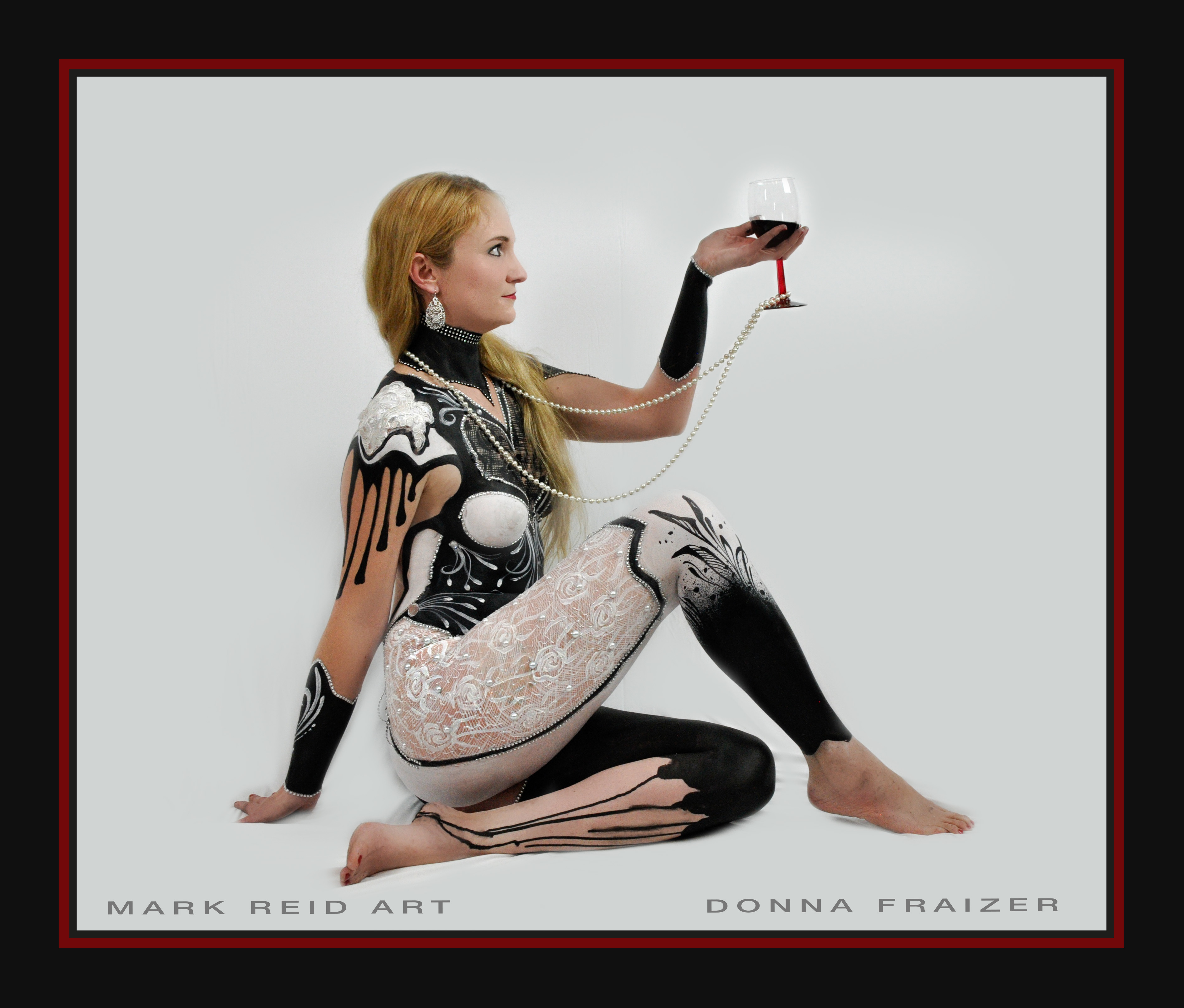 Side view of a long haird blonde woman with her leg tucked under to the camera view holding a wine glass that she is looking at in a full body painting that is very detailed and in black and white including hints of skulls and with hints of blue