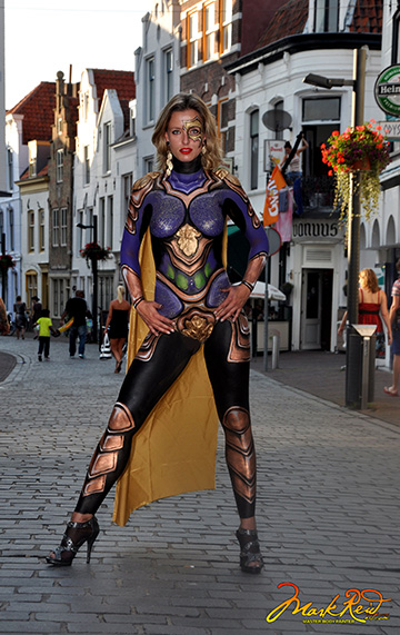 Blond model wearing blue and gold body paint with a gold cape