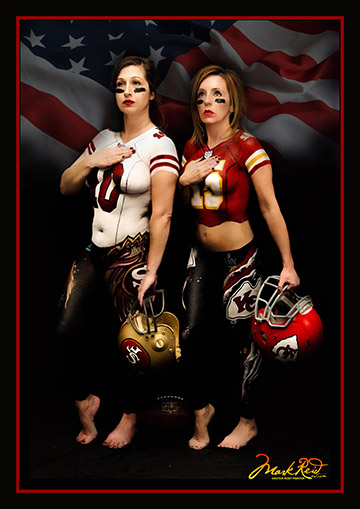 Two brunette women in full body paint that looks like football jerseys