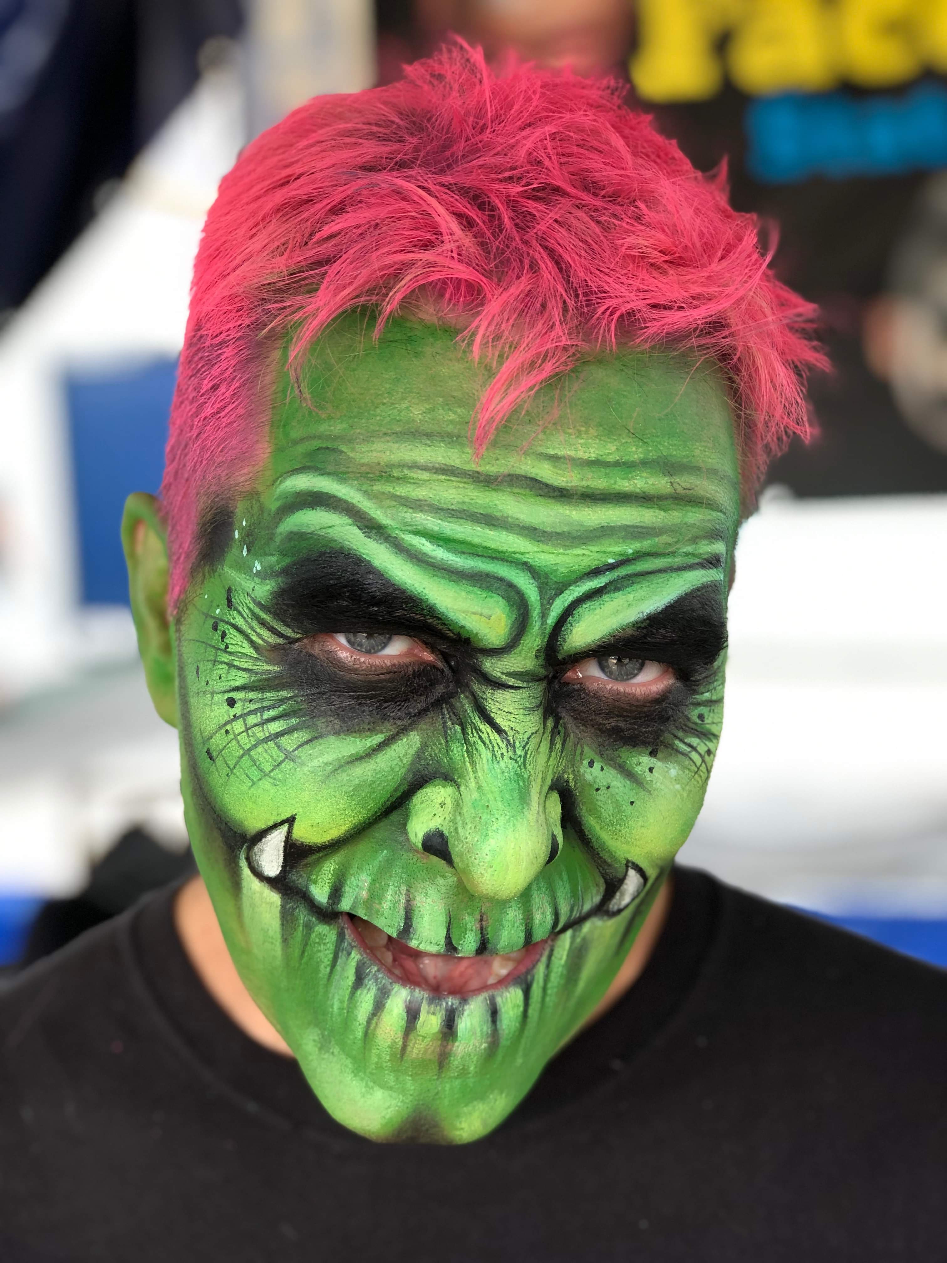 Man with a face painting that is green and looks like a monster