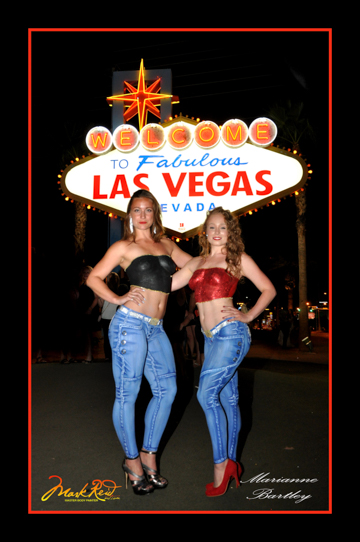 two women in front of the iconic las vegas sign in full body paint that includes corsets and jeans