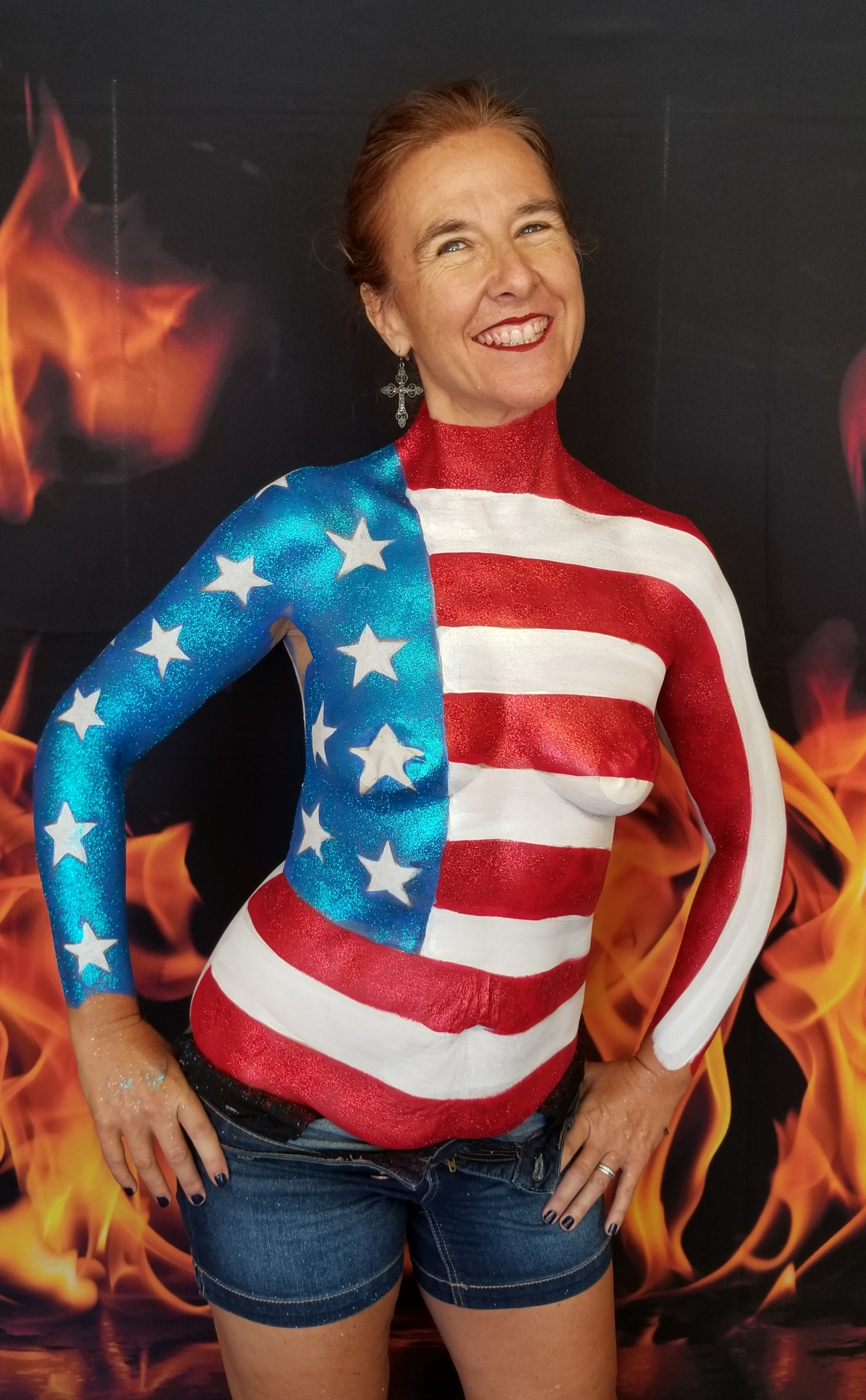 smiling model with an American flag body painted on her top half with lots glitter.