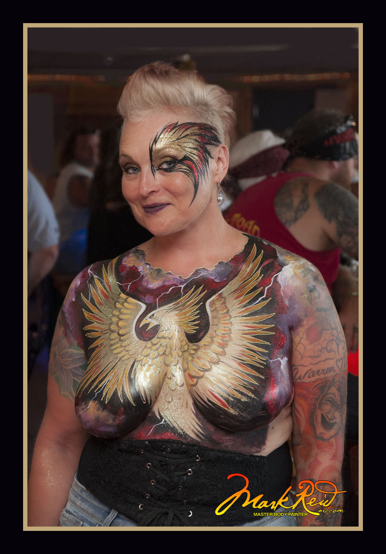 blonde model with an extremely detailed body painting featuring a metalic gold phoenix